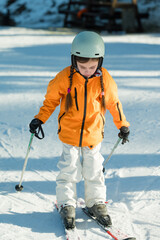 Young skier practicing balance on snowy slopes during winter, showcasing determination and fun in...