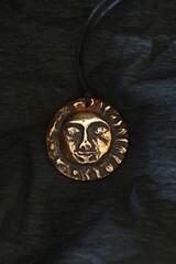 Bronze Pendant with Ancient Sun Face on Black Background, Mystical Jewelry and Celestial Symbolism.