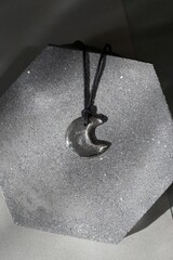 Crescent Moon Handmade Pendant on Textured Surface. Minimalist Jewelry Still Life, Dark Aesthetic.