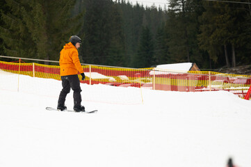 Snowboarder gracefully navigating the snowy slopes of a serene mountain resort on a cloudy winter...
