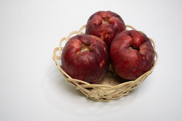 Close up of fresh Jamaican guavas neatly arranged in a small rattan basket.