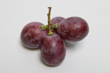 Fresh red grapes placed on a smooth white surface.