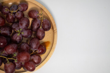 Fresh red grapes with stems on a wooden plate