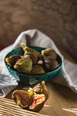 Juicy figs in a ceramic bowl on a wooden table - still life with natural light