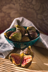 Juicy figs in a ceramic bowl on a wooden table - still life with natural light