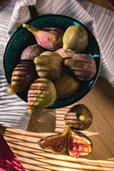 Juicy figs in a ceramic bowl on a wooden table - still life with natural light