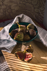 Juicy figs in a ceramic bowl on a wooden table - still life with natural light