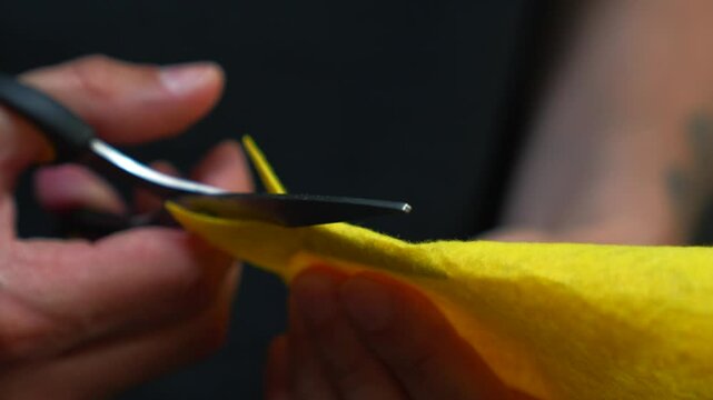 Tailor's hands cutting yellow fabric with scissors in a sewing workshop.
A man uses scissors to cut something.
Scissors, sharp, couturier, blade, material, fabric