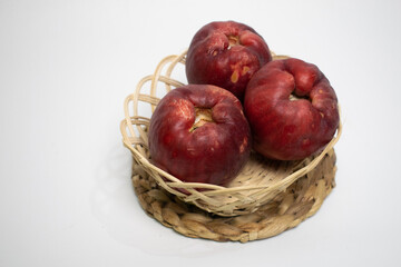 Three ripe Jamaican guavas are placed in a rustic style basket, perfect for a natural fruit display.