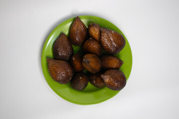 Exotic snake fruit served on a bright green plate.