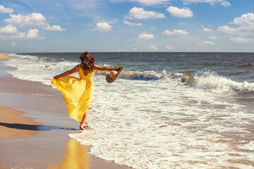 Seascape on a sunny day in summer. Woman on the beach, summertime. Young happy woman walks carefree...