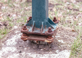 A rusted metal pole with a green base