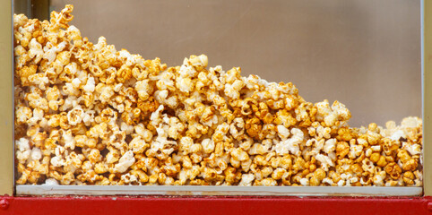 A large pile of popcorn is sitting in a red container