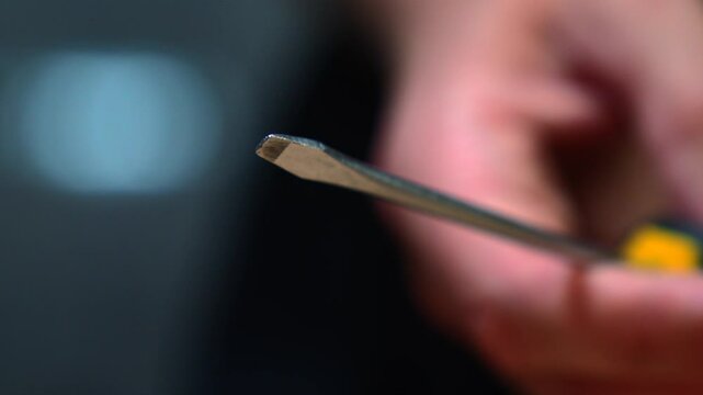 A metal screwdriver in the hands of a repairman.
Steel screwdriver for unscrewing and screwing screws and bolts
