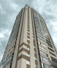 A tall building with a lot of windows and a cloudy sky in the background