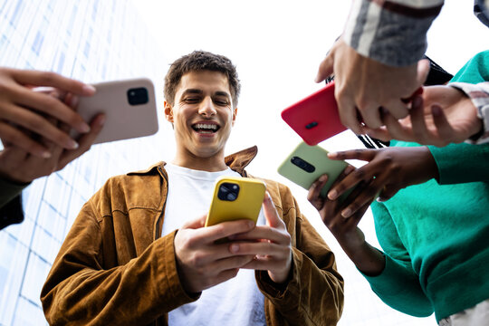 Young man showing smartphone content to his friends outdoors