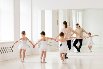 ballet teacher trains young children for a classical performance.