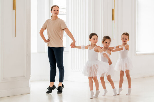 teacher leads a group of little ballerinas in white tutus