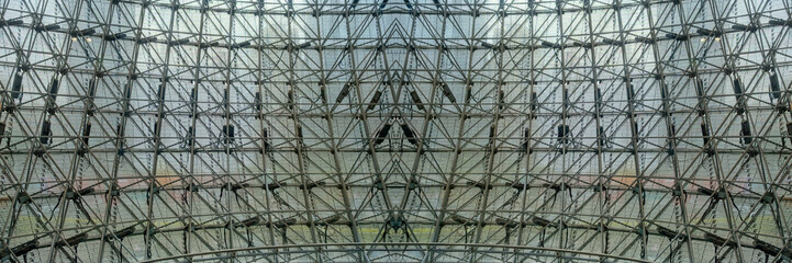 a complex metal ceiling framework structure, behind the LED wall screen panel from skyscraper