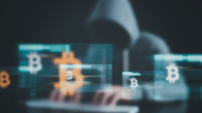 Cybersecurity Breach: A hooded figure, obscured in shadow, is focused on cryptocurrency hacking, with bitcoin symbols superimposed.