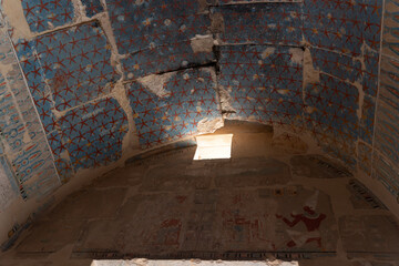 Sunlight entering ancient egyptian tomb through damaged ceiling revealing starry sky and wall...