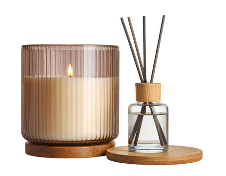 A lit cream-colored candle in a ribbed glass holder sits next to a reed diffuser with wooden sticks in a clear liquid, both placed on round wooden bases.