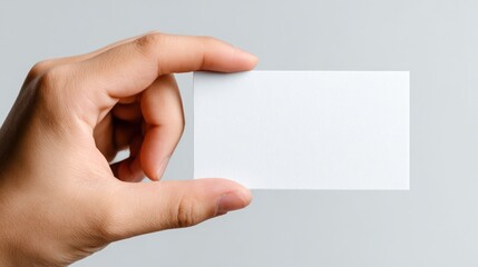 Obraz premium Human hand holding a blank white rectangular ticket horizontally, fingers gently gripping edges, isolated on clean white background, perfect for event pass or coupon mockups