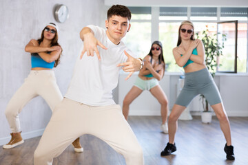 Emotional young b-boy dancing with group of female friends in dance studio. Hip-hop generation..