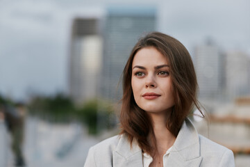 confident woman in light gray blazer with urban cityscape background thoughtful expression fashion...