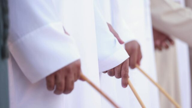 Traditional Emirati Al Ayala male dance, hands in frame holding bamboo canes. UAE heritage and unity concept.