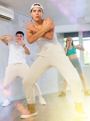 Positive emotional girl performing krump movements with group in modern dance studio. Form of...