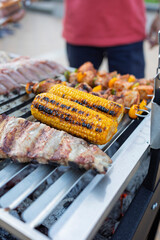 Chef grilling corn on the cob, ribs and kebabs for a summer barbecue