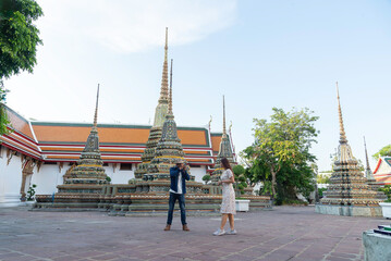 Asian couple tourists visiting Thai temple in Bangkok Thailand on summer holidays