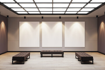 Contemporary gallery room with three vertical blank canvases under spotlights and benches on wooden...