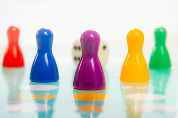 Colorful plastic pawns in a row on game board depicting teamwork and playful competition