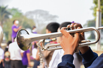 A student plays the trumpet in a school marching band during outdoor practice, focusing on teamwork, discipline, and musical performance.