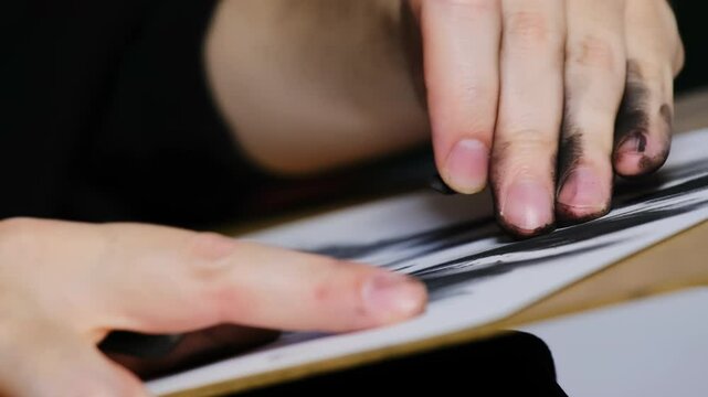 Professional makes strokes on material surface creating figure. Artist holds piece of pastel and uses technique to apply substance to sheet surface