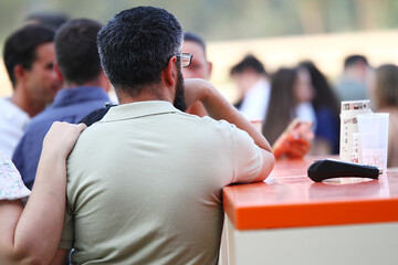 Hombre apoyado en la barra de un bar terraza con datáfono TPV para pagar