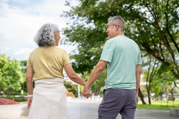 Obraz premium Glasses old man and old woman holding hand and walking together with a smile after exercise in park