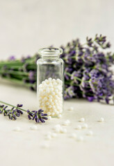 Lavender herbal flower blossoms with white round homeopathy pills in medical bottle. Homeopathy concept