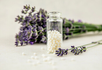 Lavender herbal flower blossoms with white round homeopathy pills in medical bottle. Homeopathy concept