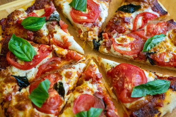 Pizza basil tomatoes: Freshly baked pizza, topped with basil, and tomatoes, served immediately for a flavorful meal.