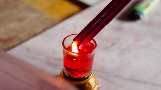A close-up scene of a hand lighting incense using a small traditional oil lamp, captured in a peaceful Yunnan temple setting &ndash; symbolizing prayer, respect, and tranquility.