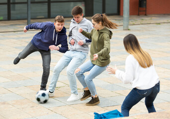Group of teenagers playing soccer with ball outdoors and having fun