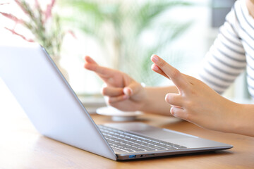 Woman hands crossing fingers waiting in front of a laptop