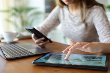 Woman hands using multiple devices browsing on tablet