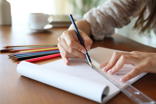 Woman hand using pencil and ruler to draw on notebook