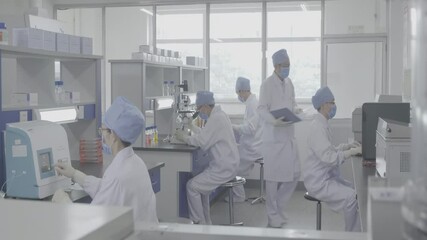 Scientists wearing clean lab coats work meticulously in a well-illuminated, sterile laboratory, focusing on pathogen research and disease analysis, highlighting collaboration in microbiology. - Powered by Adobe