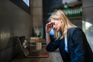 Tired businesswoman sitting with laptop on desk at office