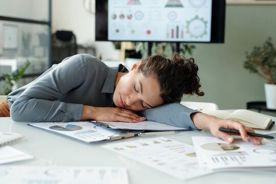 Businesswoman asleep at desk with financial charts in office